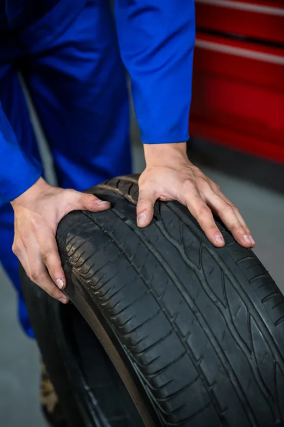 Tyre mechanic showing a worn tyre signalling replacement
